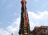 Kathmandu Patan 03 Rato Machhendranath Chariot The Rato Macchendranath wooden-wheeled chariot sad idle in the street of Patan waiting to be moved later in the day. It has a very unwieldy tall spire made from bamboo poles raised from four ends of the chariot, making the chariot balance precariously. Rato (Red) Macchendranath is the god of rain and plenty, and is a tantric version of Avolokiteshvara to Buddhists and a version of Shiva to Hindus. This is the longest and most important festival of Patan, beginning with building the chariot, and then towing the chariot through the streets of Patan every day for a month, ending just before the monsoon.